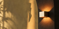 Minimalist rechargeable wall light glowing in warm evening light, mounted without a cable