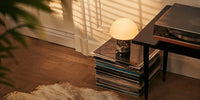 Tavellio marble mushroom table lamp glowing softly atop a stack of vinyl records beside a vintage record player.