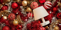 Small cordless table lamp among red and gold Christmas baubles and tinsel