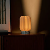 Cordless table lamp Alba casting warm light against a moody olive wall with marble base detail