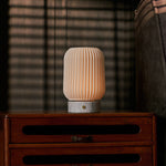 Alba cordless table lamp in Bianco Statuarietto white marble and porcelain lighting a striped-blind bedroom