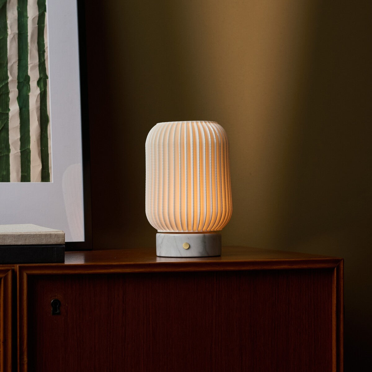 Tavellio Alba cordless table lamp with Bianco Statuarietto marble base glowing on a walnut sideboard