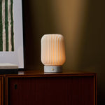 Tavellio Alba cordless table lamp with Bianco Statuarietto marble base glowing on a walnut sideboard