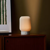 Tavellio Alba cordless table lamp with Bianco Statuarietto marble base glowing on a walnut sideboard