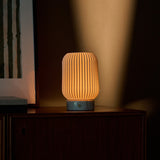 Alba rechargeable table lamp in Bianco Statuarietto white marble and porcelain reflected in a bedroom mirror