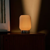 Alba rechargeable table lamp dimmed low, Calacatta Viola marble base on a dark wood console