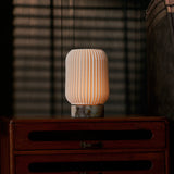 Alba cordless table lamp with Calacatta Viola marble on a nightstand under blind-cast light