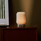 Alba cordless table lamp in Calacatta Viola marble glowing on a walnut sideboard