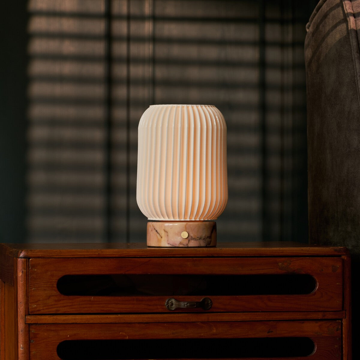 Alba Calacatta Vionaro Pink kabellose Tischlampe Tavellio – leuchtend auf Holzkommode – Lamellenschatten der Jalousie im Hintergrund