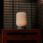 Alba cordless table lamp on a bedroom nightstand with sunlit blind-shadow stripes