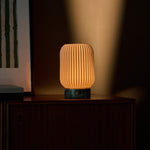 Alba rechargeable table lamp dimmed low, warm glow on a walnut sideboard at dusk