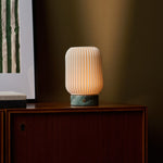 Alba cordless table lamp glowing on a wood sideboard against an olive green wall