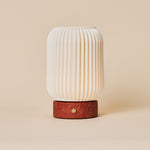 Rechargeable table lamp Alba in red travertine and porcelain, fluted shade viewed straight-on