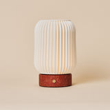 Rechargeable table lamp Alba in red travertine and porcelain, fluted shade viewed straight-on