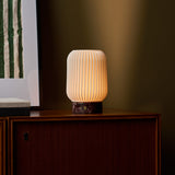 Tavellio Alba rechargeable table lamp with Rosso Levanto marble base glowing on a walnut sideboard
