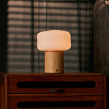 Andrew bois clair lampe de table rechargeable Tavellio – devant des stores vénitiens, près d'un fauteuil à rayures roses