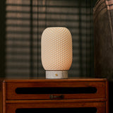 Aurora cordless table lamp with dimpled porcelain shade beside a sofa near window blinds