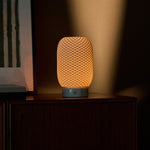 Aurora cordless table lamp in Bianco Statuarietto marble and porcelain glowing on a wooden sideboard