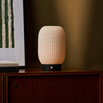 Tavellio Aurora rechargeable table lamp casting warm light beside a framed print and books on a sideboard