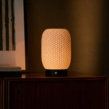 Cordless table lamp Aurora glowing warmly at dusk, reflection visible in a nearby picture frame