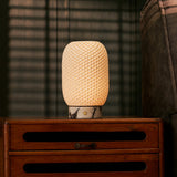 Rechargeable table lamp Aurora in Calacatta Vionaro marble and porcelain lit on a wood credenza beside framed wall art