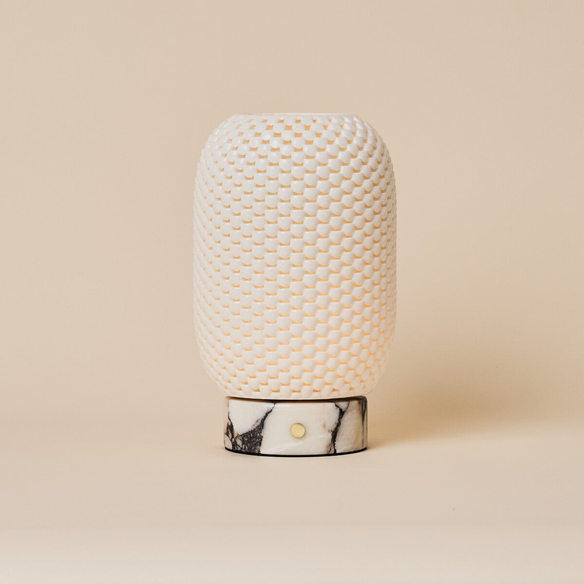 Cordless table lamp Aurora in Calacatta Vionaro marble and porcelain glowing on a wooden dresser beside a sofa