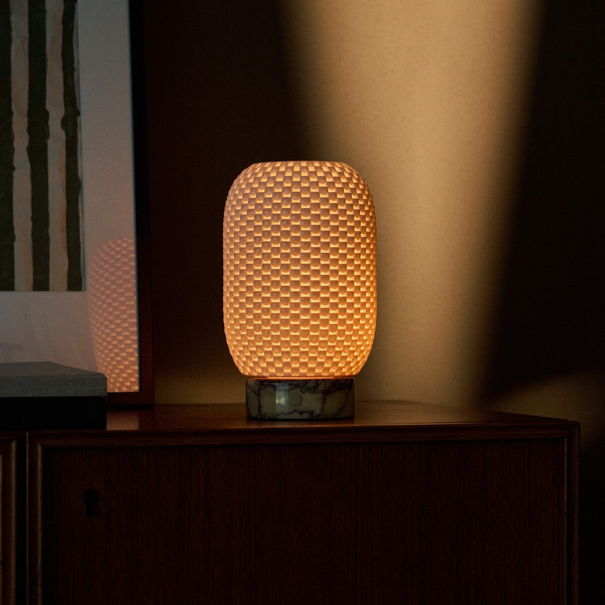 Aurora rechargeable table lamp in yellow Calacatta Vionaro marble glowing on a wood sideboard at dusk