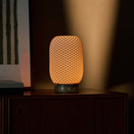 Aurora rechargeable table lamp in yellow Calacatta Vionaro marble glowing on a wood sideboard at dusk