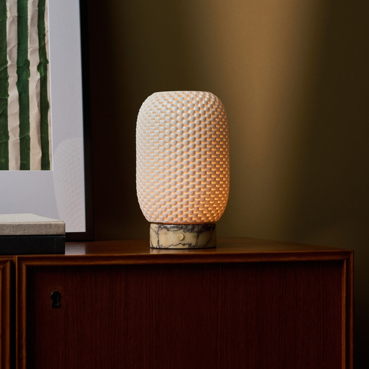 Aurora rechargeable table lamp in yellow Calacatta Vionaro marble on a walnut cabinet by an olive wall