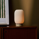 Aurora rechargeable table lamp in yellow Calacatta Vionaro marble on a walnut cabinet by an olive wall