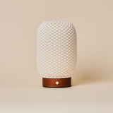 Aurora Chestnut Brown rechargeable lamp with woven porcelain shade and reddish wood base on beige backdrop