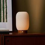 Aurora Chestnut Brown cordless lamp glowing on a wood sideboard against an olive green wall