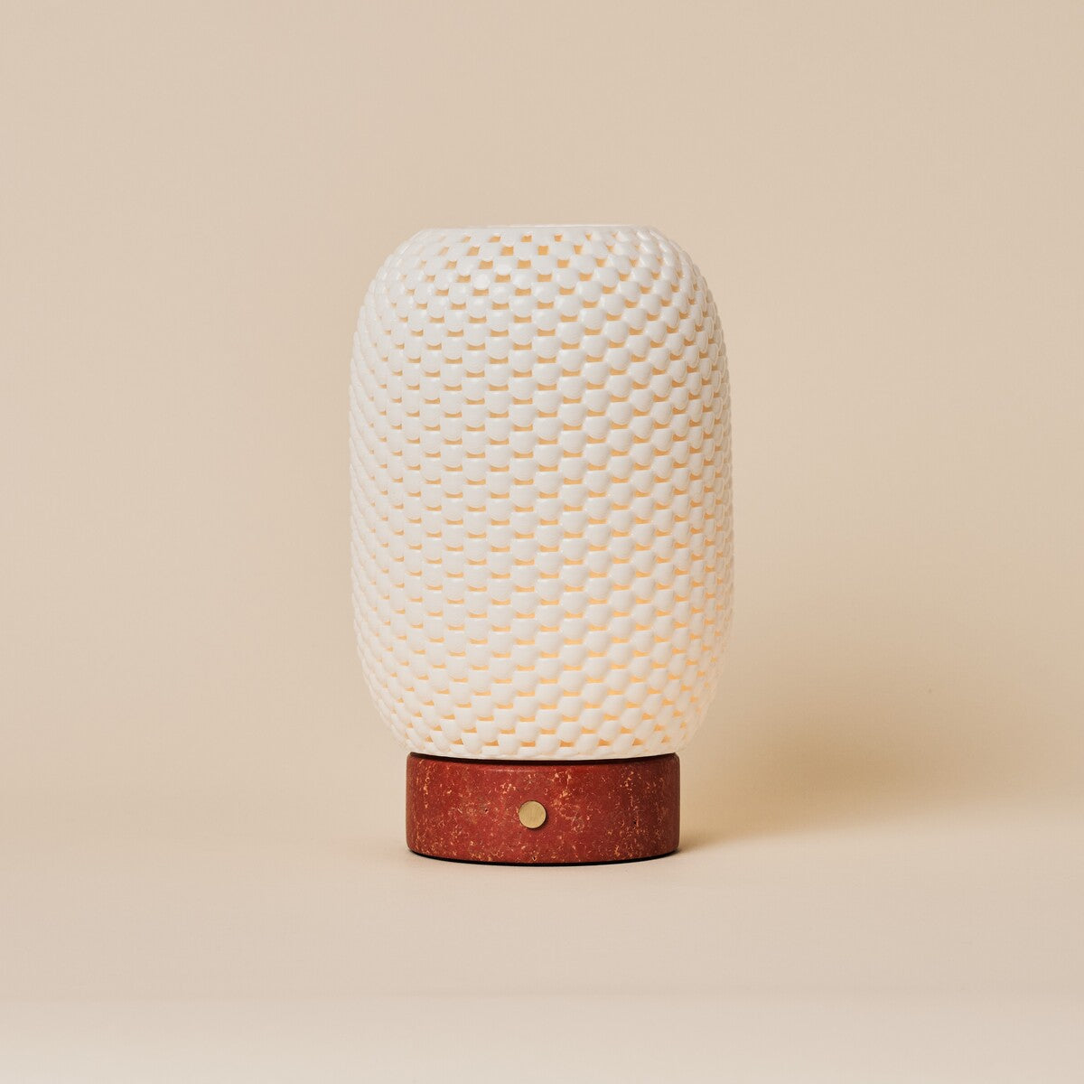 Cordless table lamp Aurora in Red Travertine and porcelain glowing on a wooden dresser beside a sofa