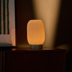 Cordless table lamp, Aurora Silver Travertine and Porcelain design, casting warm light in a dim evening corner