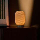 Cordless table lamp, Aurora Silver Travertine and Porcelain design, casting warm light in a dim evening corner