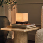 Barent marbre Emperador Dark lampe de table rechargeable Tavellio - sur guéridon rond en travertin - à côté d'un olivier en pot et de livres