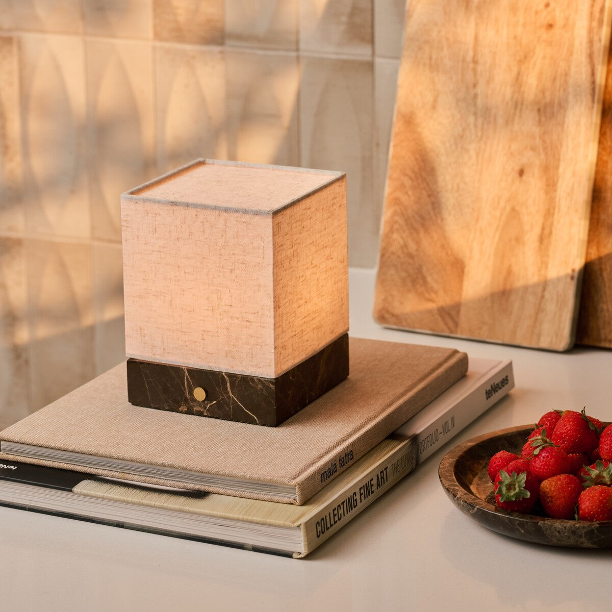 Barent marbre Emperador Dark lampe de table rechargeable Tavellio - posée sur des livres empilés - bol de fraises fraîches à côté