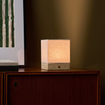 Barent travertin Classic lampe de table sans fil Tavellio - éclairant une commode en bois foncé - sous un tableau à rayures vertes