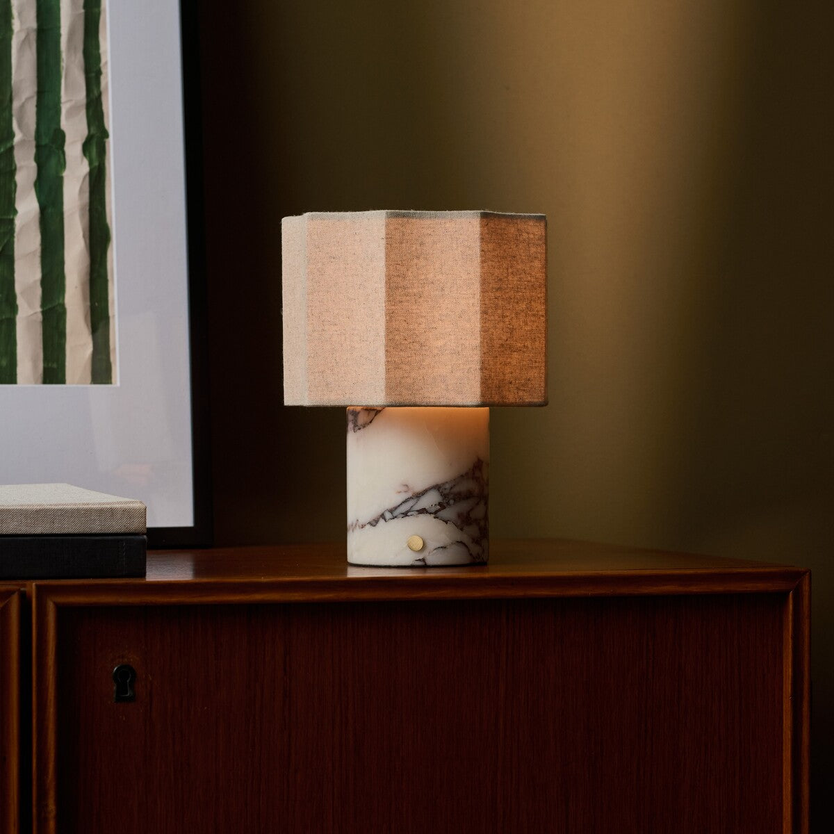 Tavellio Bonnard rechargeable table lamp lit on a wood sideboard against an olive green wall