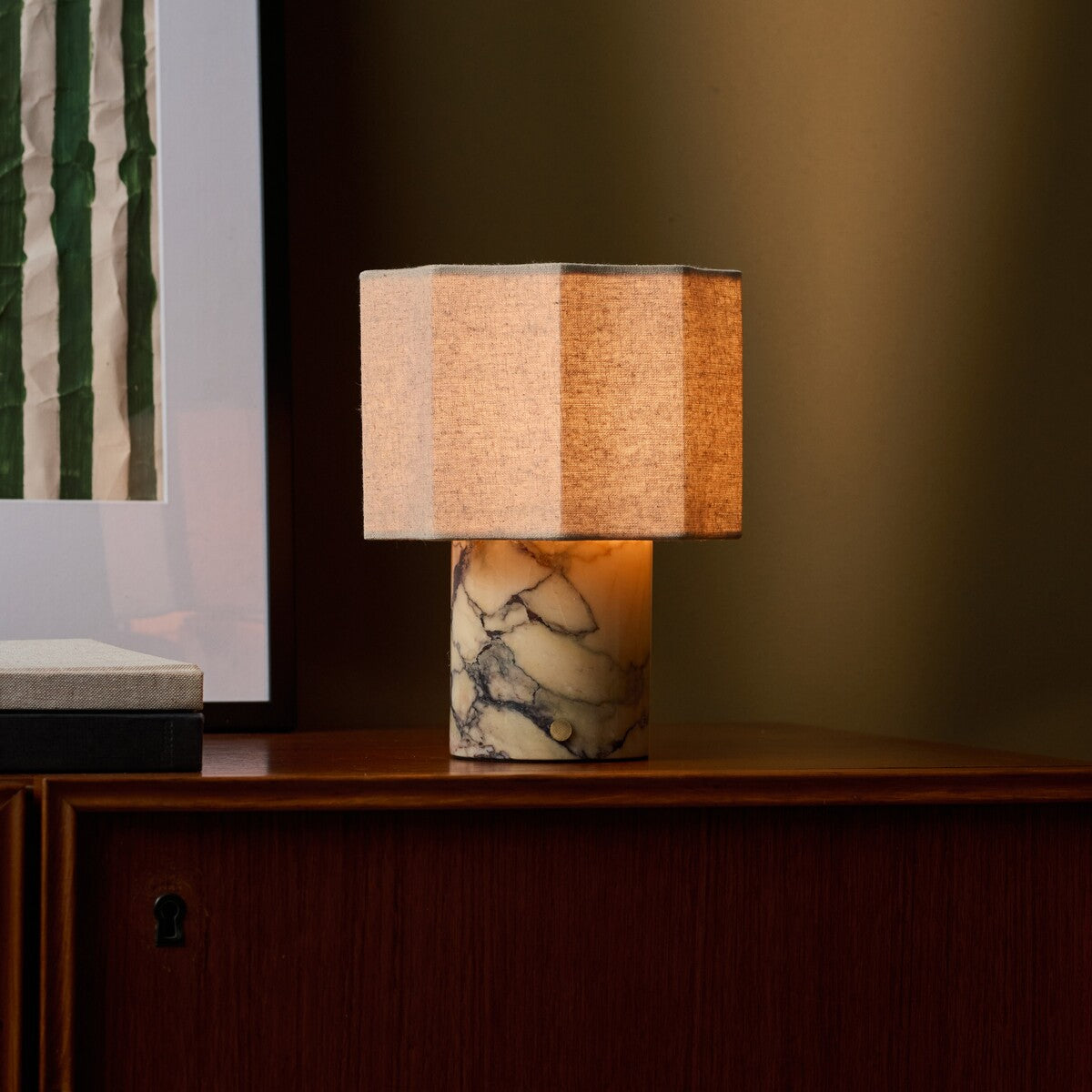 Bonnard cordless table lamp with yellow Calacatta Vionaro marble base glowing beside a green striped artwork print