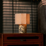 Bonnard cordless table lamp in yellow Calacatta Vionaro marble glowing on a wooden nightstand beside a striped sofa