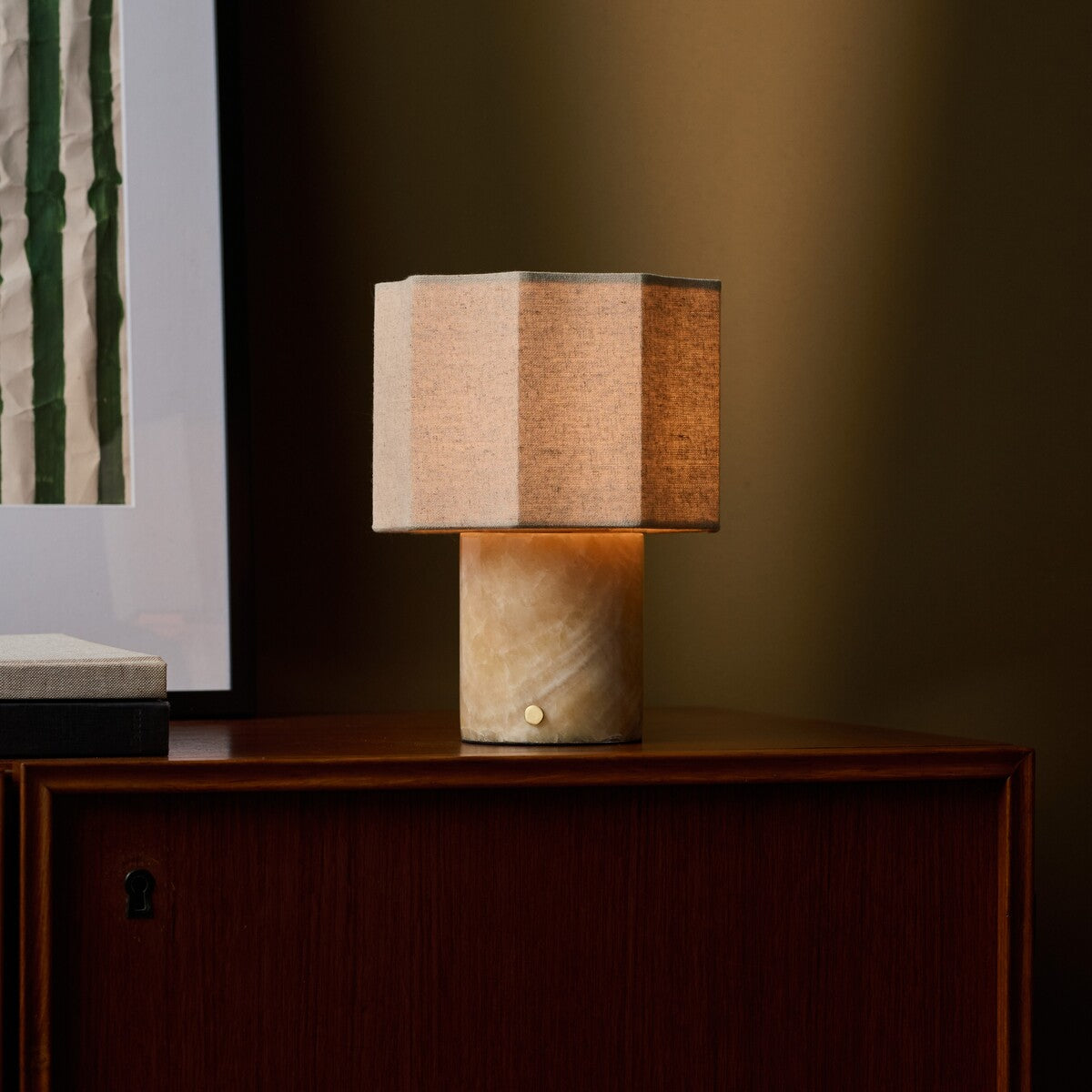 Bonnard Honey Onyx lampe de table sans fil Tavellio – sur un meuble en bois foncé – tableau à rayures vertes derrière