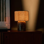 Cordless table lamp Bonnard Large in Emperador dark marble casting warm light on a walnut sideboard at dusk