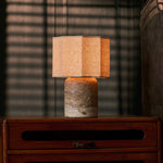 Cordless table lamp Bonnard Large in silver travertine on a wood nightstand beside sunlit blinds