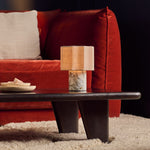 Cordless Bonnard table lamp glowing on a dark coffee table beside a rust red velvet sofa
