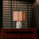 Bonnard cordless table lamp in Arabescato marble on a nightstand under venetian blind shadows