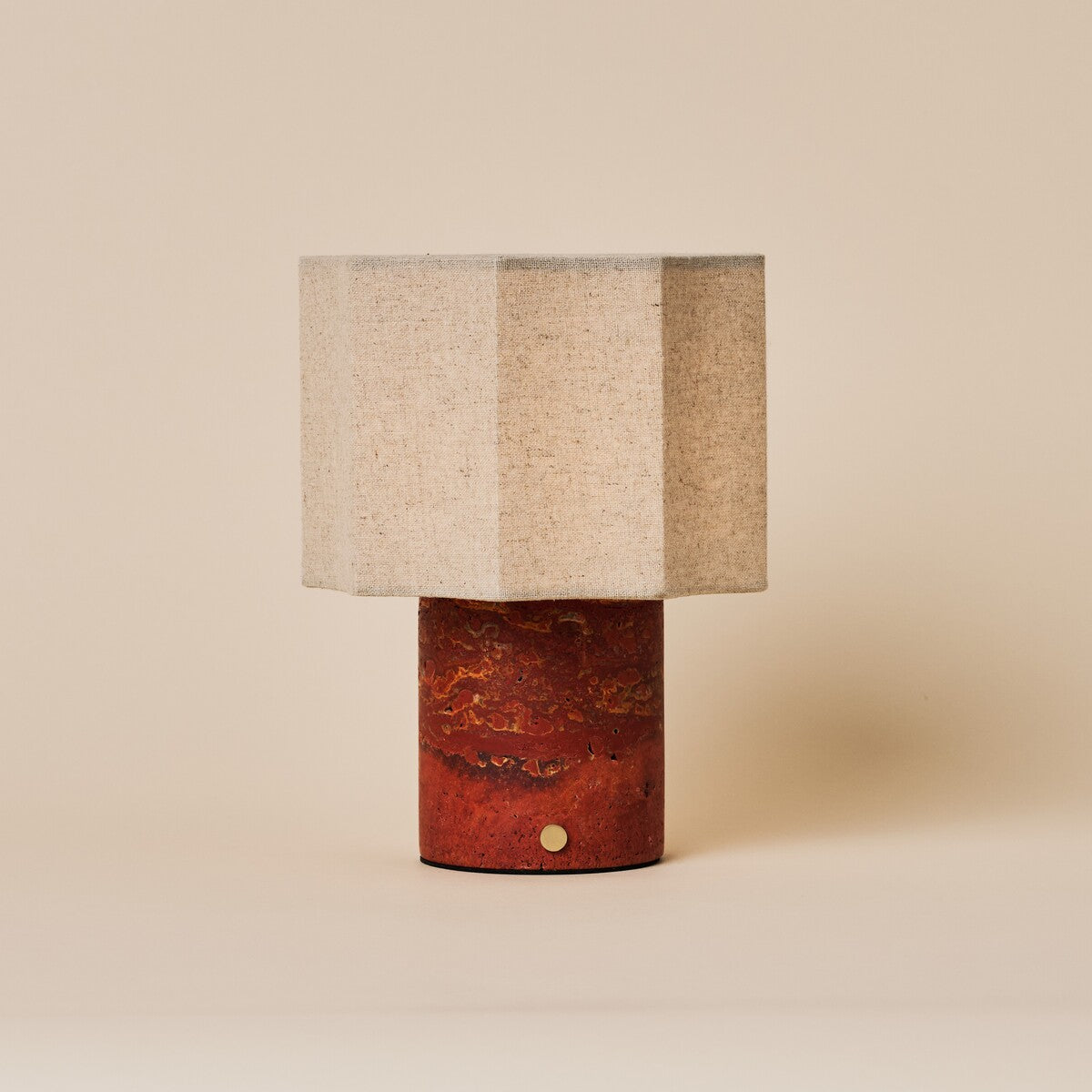 Bonnard rechargeable table lamp with a Red Travertine stone base and hexagonal linen shade on a plain backdrop