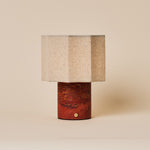 Bonnard rechargeable table lamp with a Red Travertine stone base and hexagonal linen shade on a plain backdrop