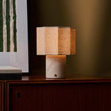 Bonnard Rosa Aurora lampe de table sans fil Tavellio – sur un meuble en bois foncé – tableau à rayures vertes derrière