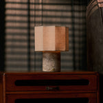 Bonnard cordless table lamp in Silver Travertine stone glowing on a teak sideboard at dusk, sofa in the backdrop